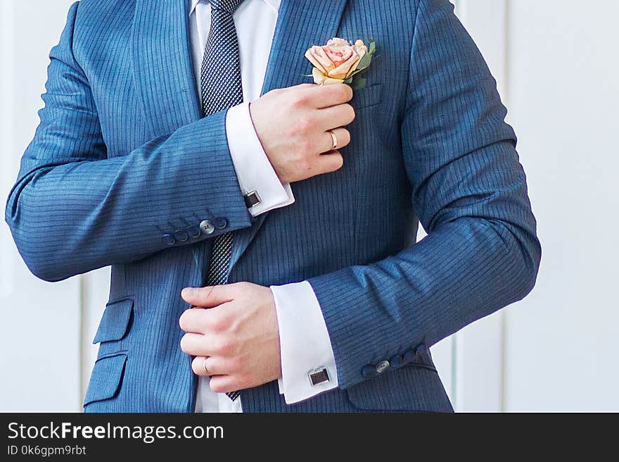 Groom straightens the flower in his buttonhole indoor closeup