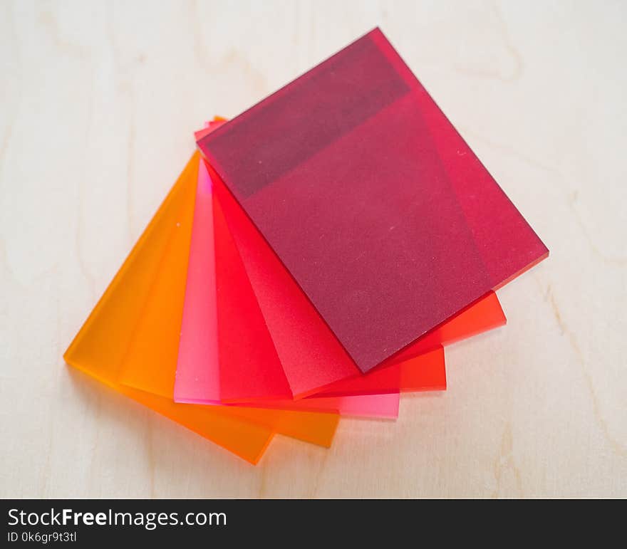 Colorful pieces of matte plexiglass on a wooden background.