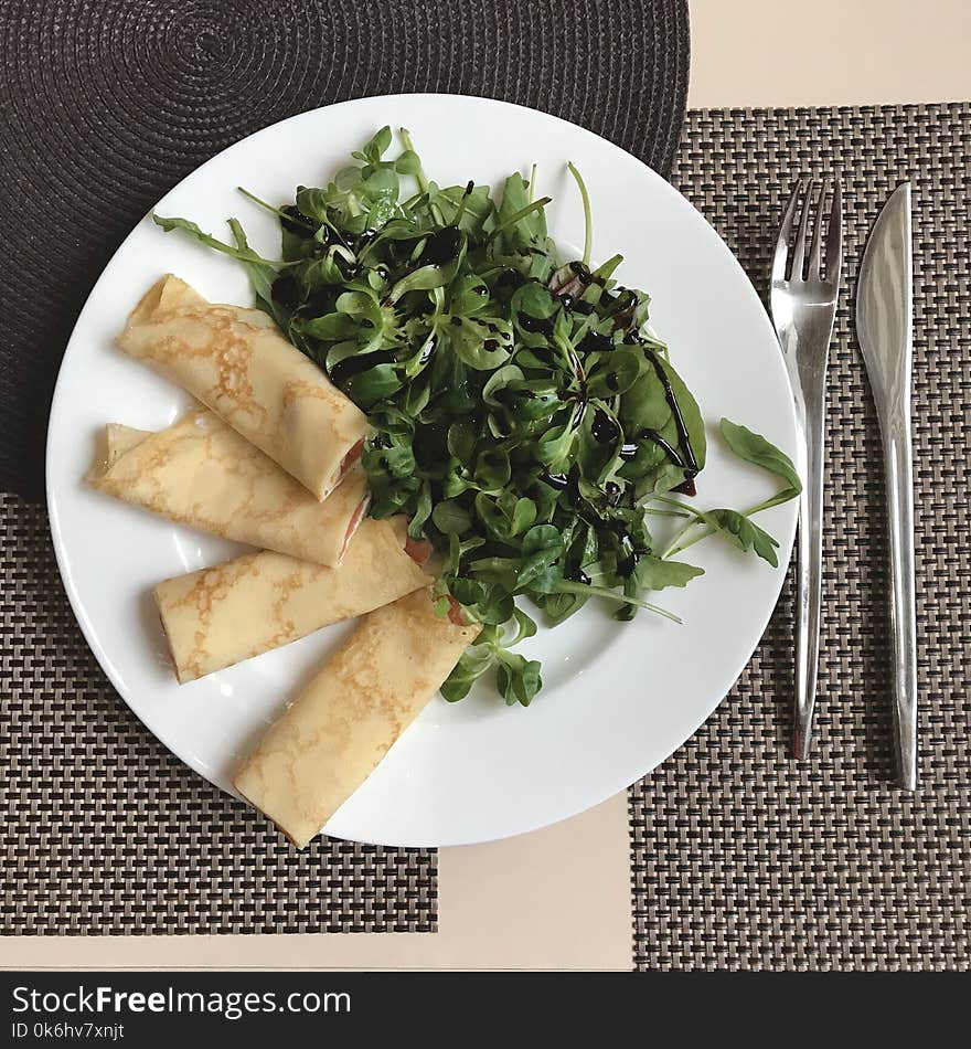 Rolled Crepes And Salad On A White Plate