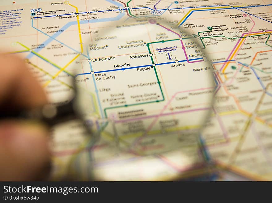 Pigalle metro station on a printed paris metro map under a magnifier lens, concept of tourism in france