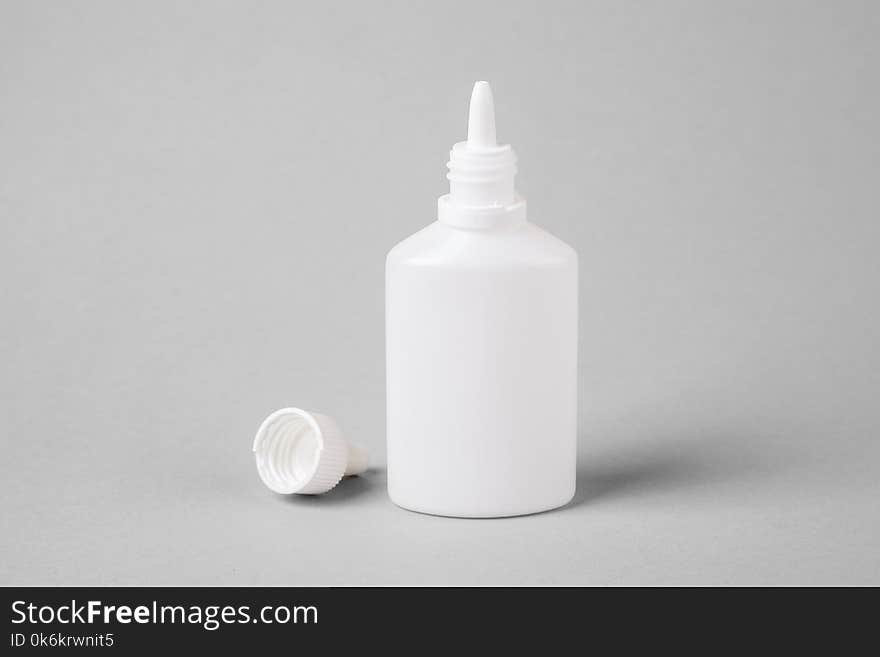 Spray for the nose in a white plastic bottle on a gray background. Aerosol from the common cold or allergy. mock-up