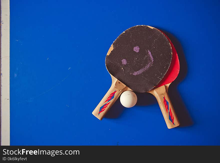 Two fryed tennis rackets on a blue tennis table background.