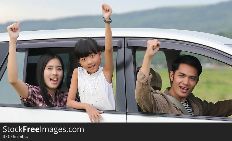 Happy little girl with asian family sitting in the car for enjoying road trip and summer vacation in camper van