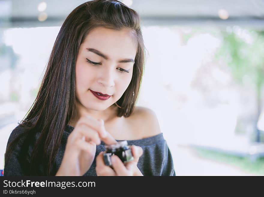 A beautiful woman asian using a skin care product, moisturizer or lotion taking care of her dry complexion. Moisturizing cream in female hands .