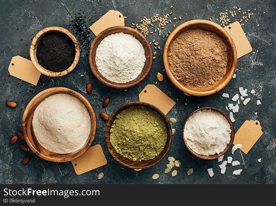 Wooden bowls of various flour and empty tags. Flour from black cumin, pumpkin seeds, wheat, flax seeds, almonds and coconut. Wooden bowls of various flour and empty tags. Flour from black cumin, pumpkin seeds, wheat, flax seeds, almonds and coconut.