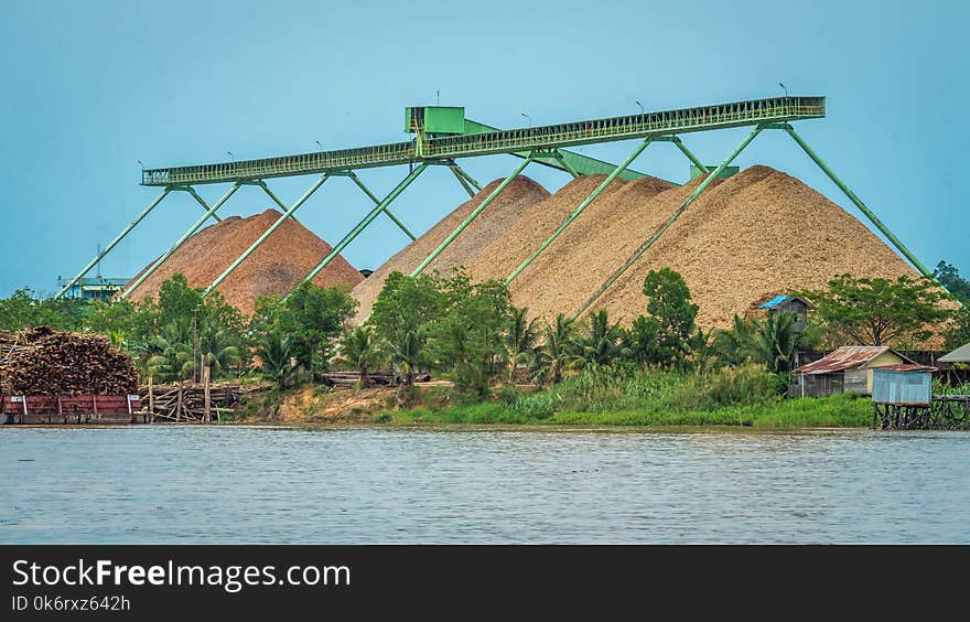 Wood chip stockpile factory on Mahakam riverbank. industrial background