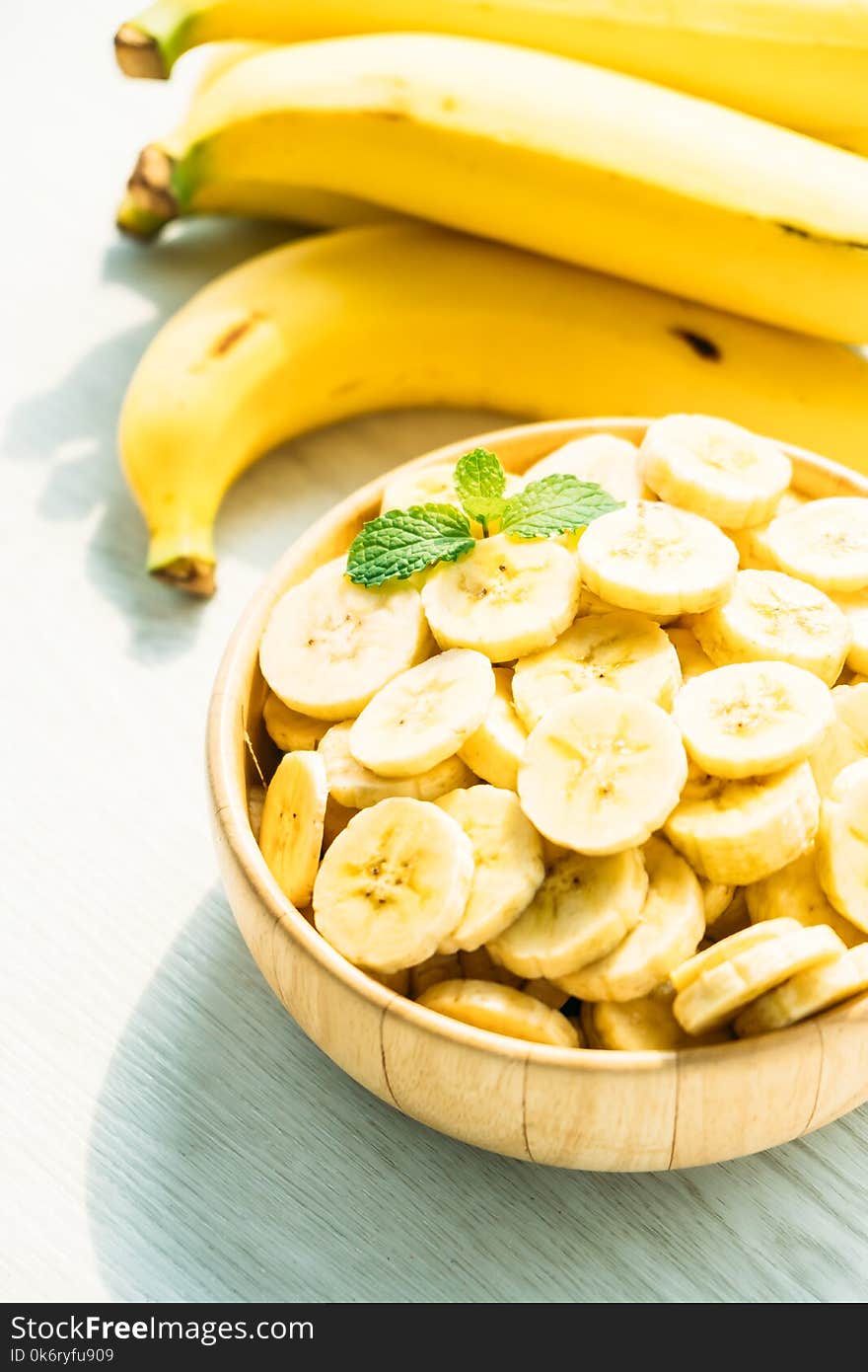 Raw yellow banana slices in wooden bowl