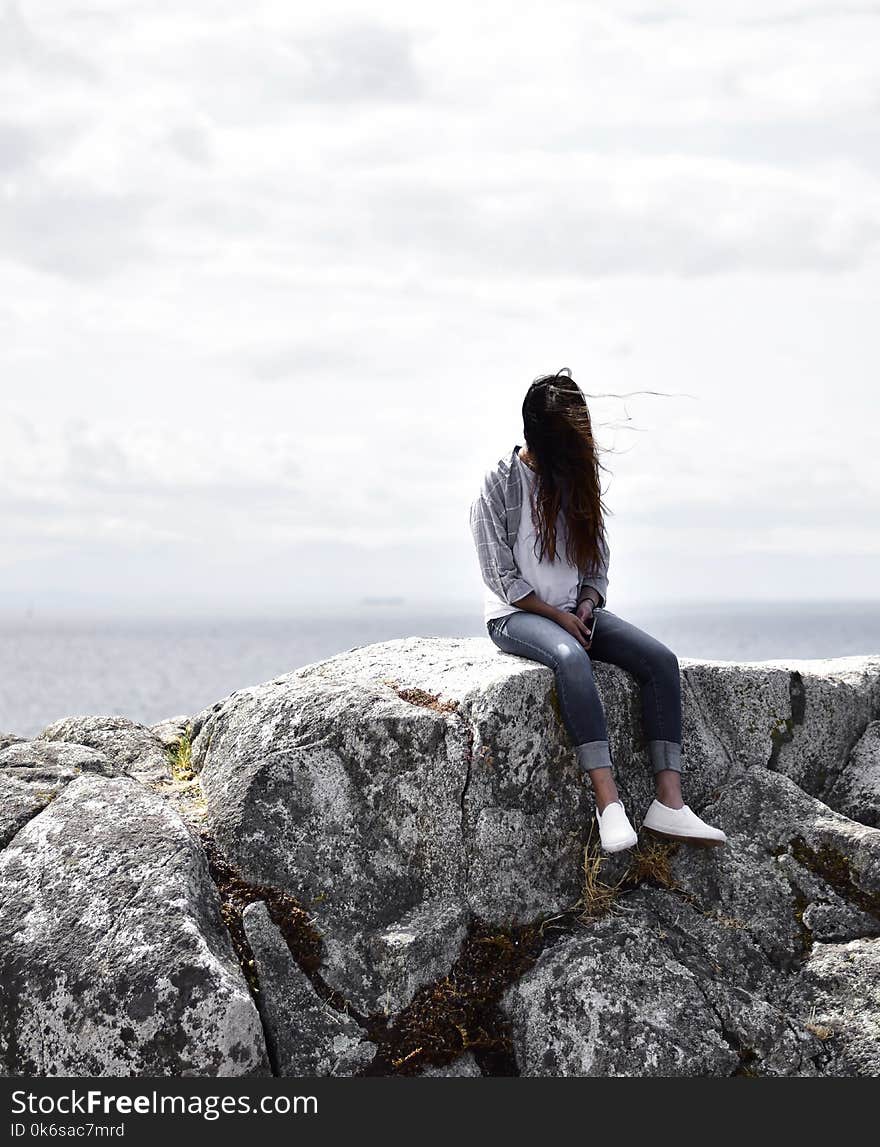 Woman Sits on Gray Rock