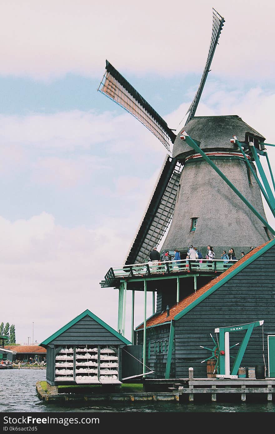 People Walking on Windmill Near Body of Water