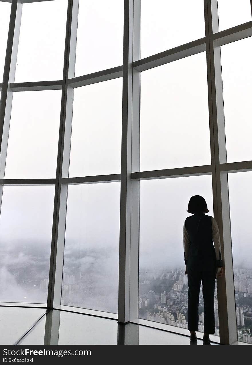 Woman Standing in Front of Glass Panel Inside Building