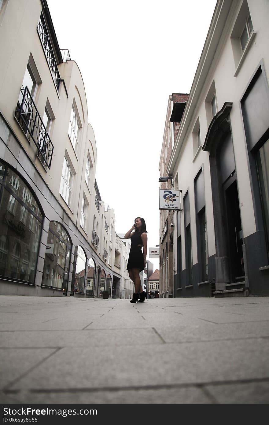 Woman Wearing Black Sleeveless Dress in Between Buildings