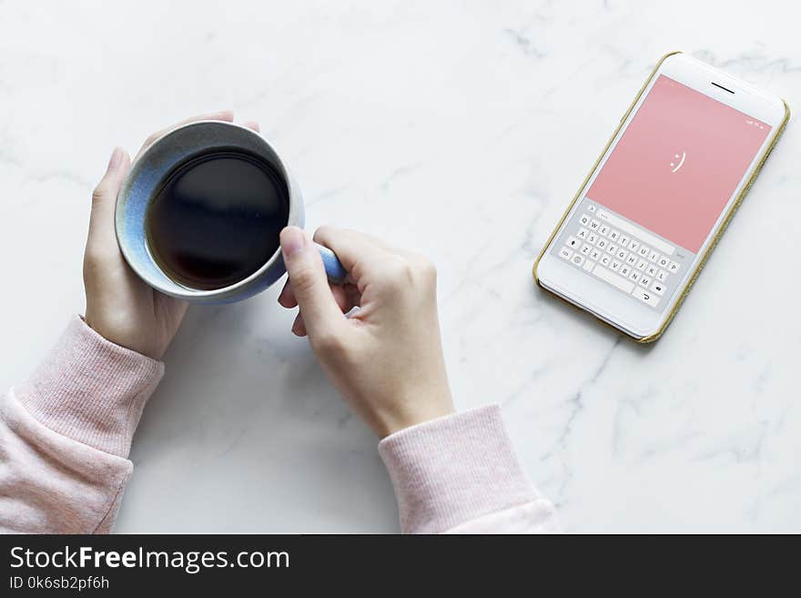 Photo of Person Holding Blue Cup Near Smartphone