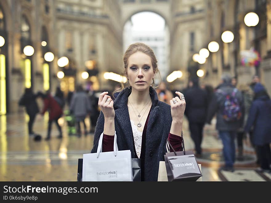 Woman Wearing Black Coat Holding Assorted-color Shopping Bags on Building