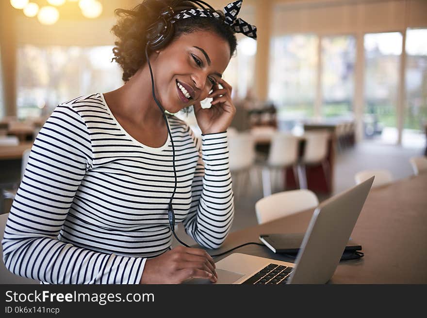 Smiling African student studying and listening to music at schoo