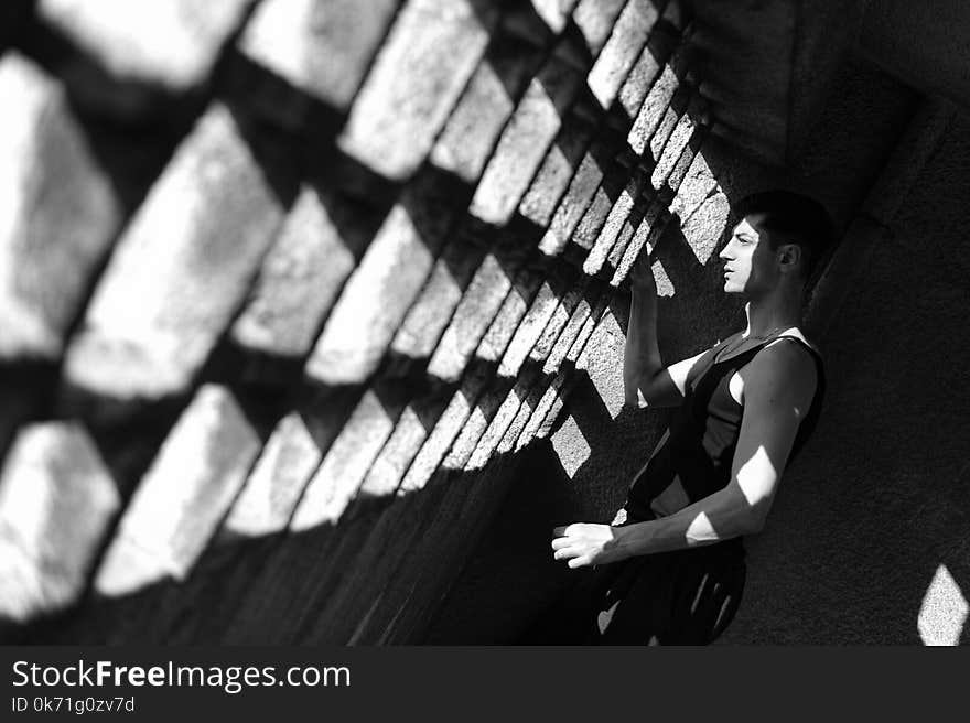 Grayscale Photo of Man Wearing Tank Top Staring at Window