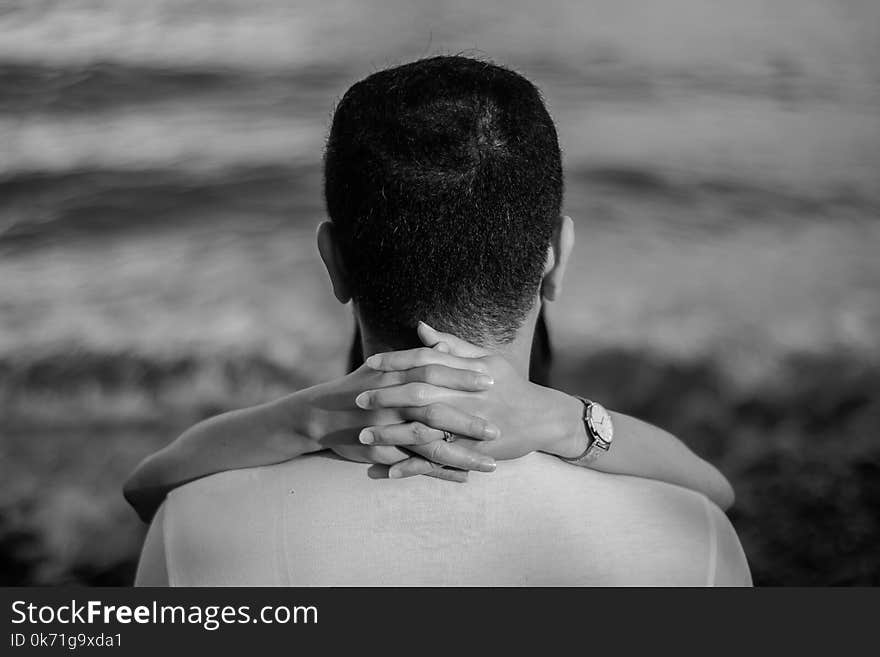 Grayscale Photo of Man Hugged by Woman