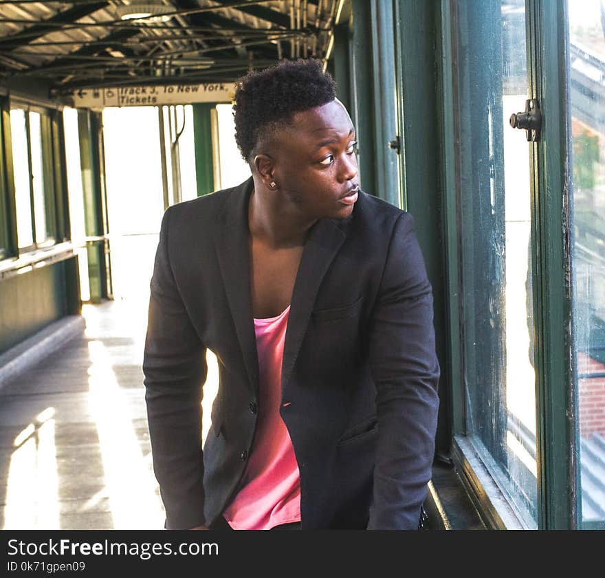 Man in Black Suit Looking Outside of a Window