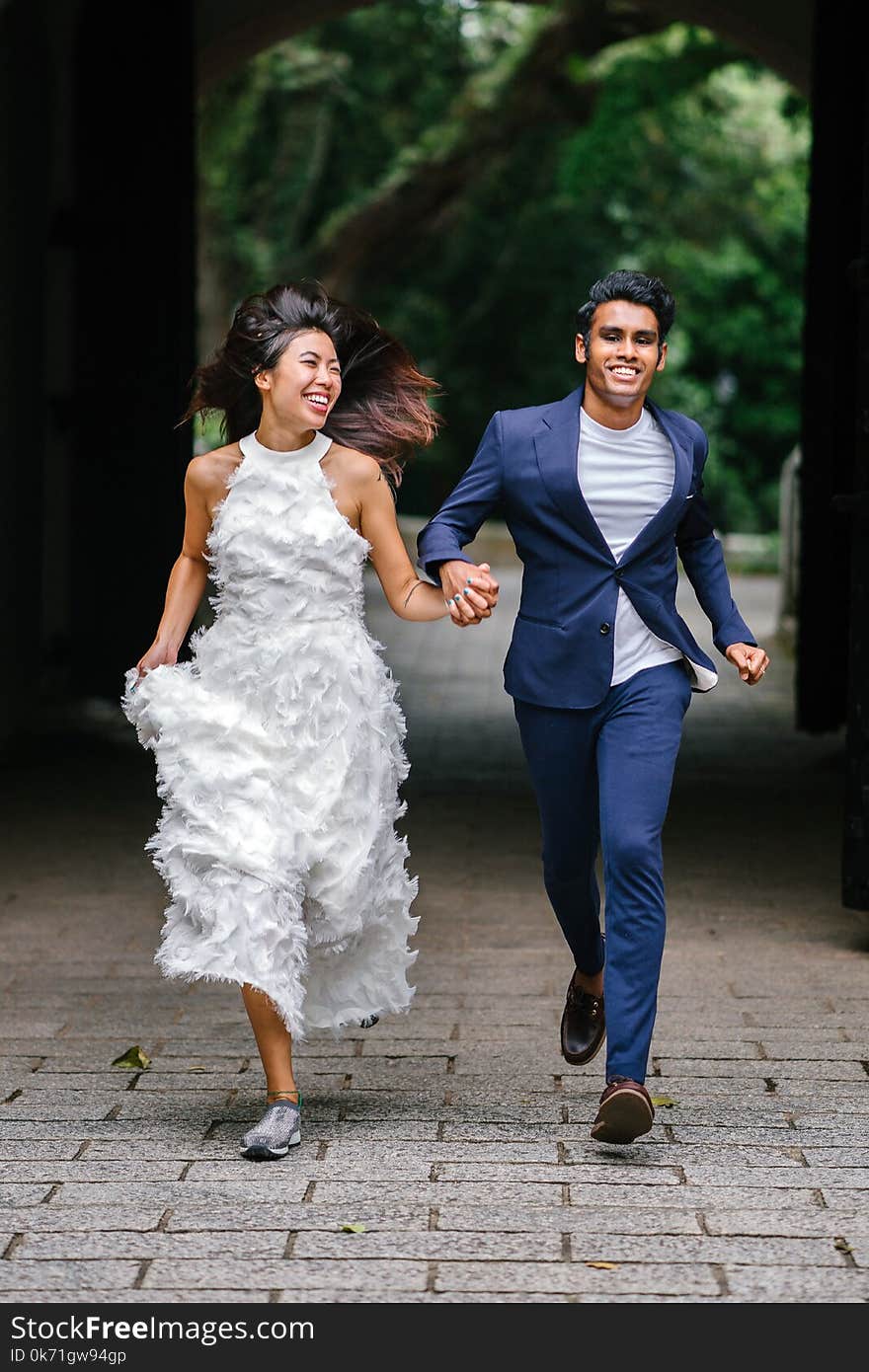 Bride and Groom Running on Concrete Pathway