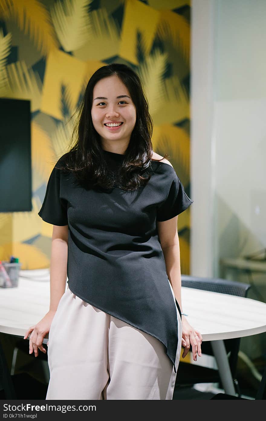 Woman Sits on White Wooden Table Behind Yellow and White Concrete Wall