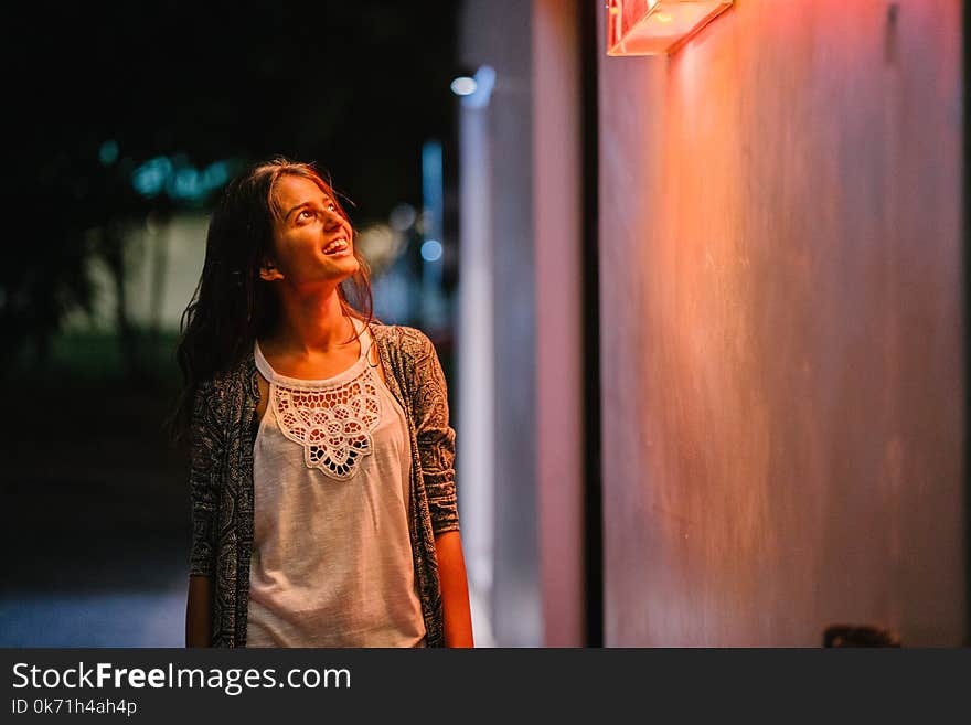 Woman in Gray Cardigan Standing Near Wall during Nighttime