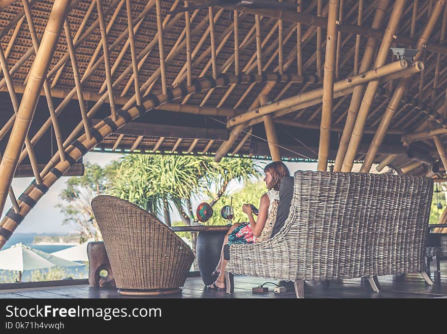 Woman Sitting On Brown Wicker Chair