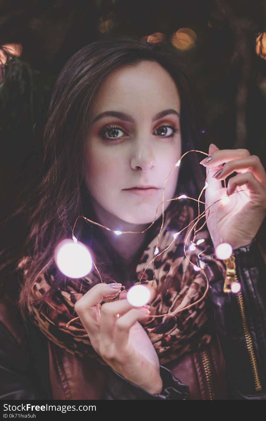 Woman Wearing Leather Jacket And Leopard Print Scarf Holding String Light