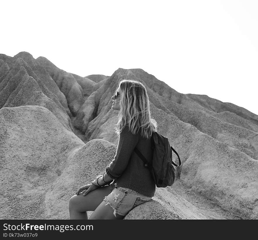 Grayscale Photo of Woman Sitting on Rock