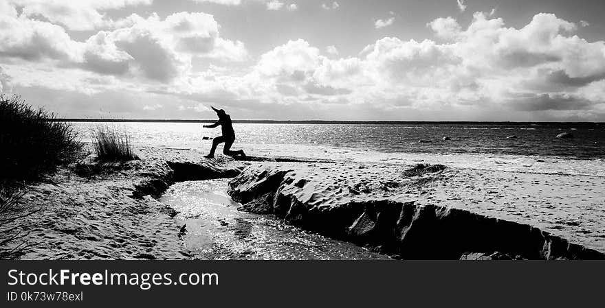 Grayscale Photography of a Person Jumping over Body of Water