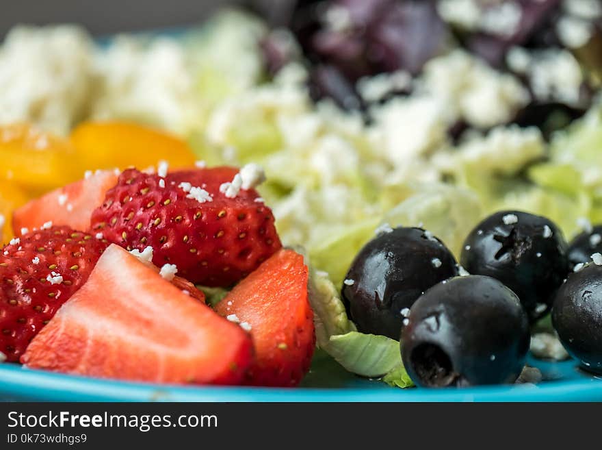 Plate of Slices of Strawberries and Green Leaf Vegetables