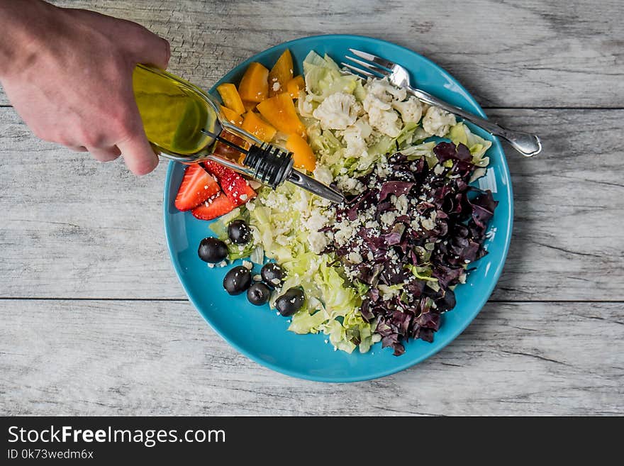 Person Pouring Vegetable Oil on Vegetable Salad