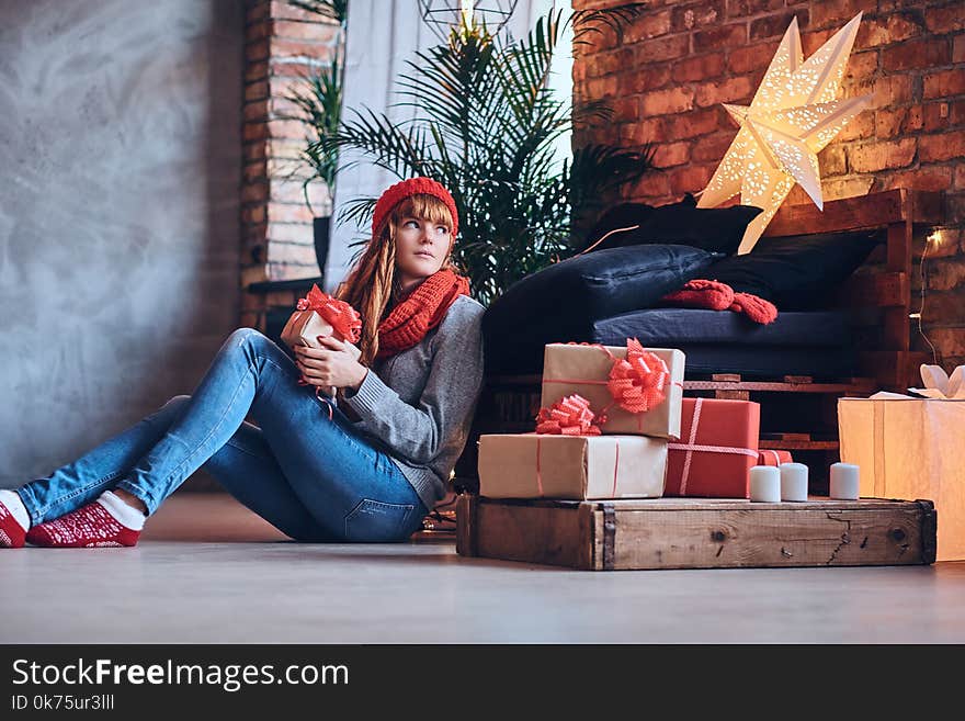 A woman holds a Christmas gift in a living room with loft interior.