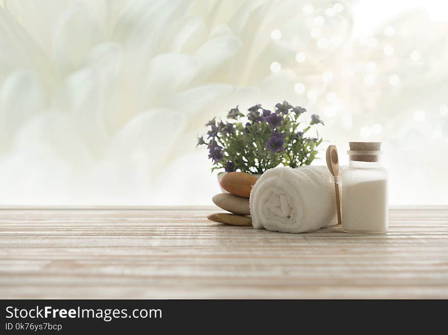 Spa treatment concept. towel,salt spa and spa stones with white flowers background. Spa treatment concept. towel,salt spa and spa stones with white flowers background