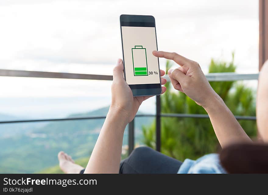 Low battery concept. young woman holding a smart phone with low battery on screen.