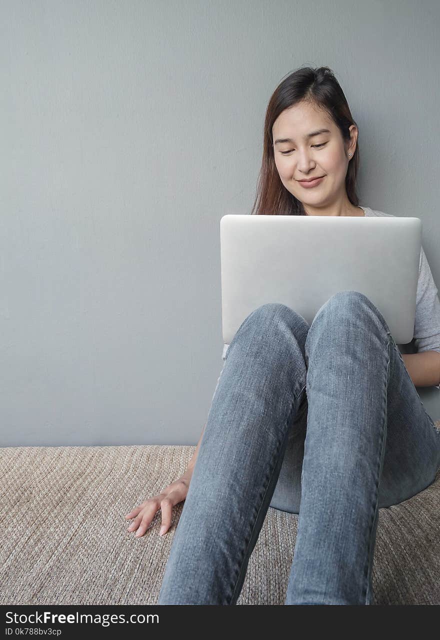 Closeup asian woman sitting for use computer notebook in work concept on blurred cement wall textured background with copy space