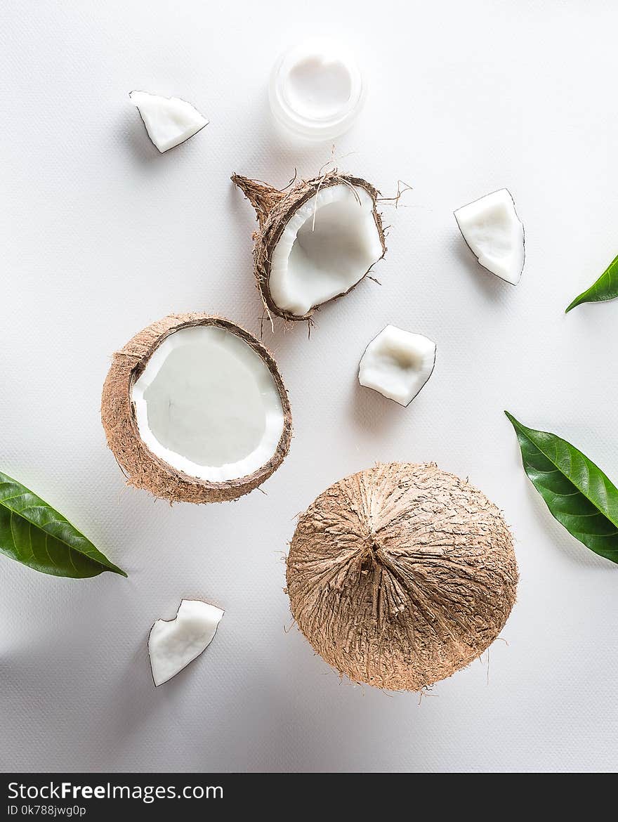 Homemade coconut cosmetic with coconut and green leaf on white background. from top view