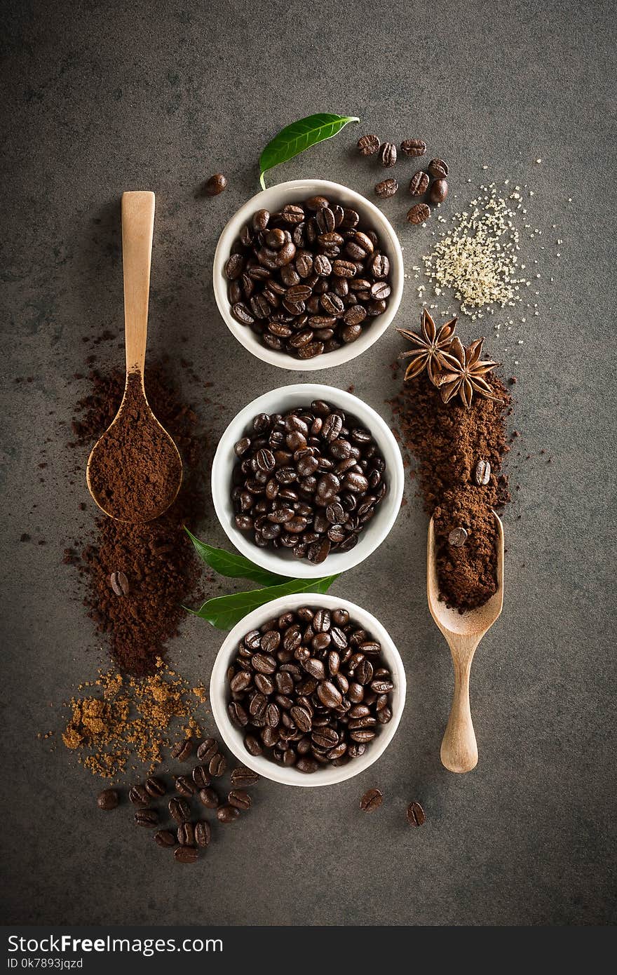 Different varieties of coffee beans with sugar and green leaf on dark vintage background. From top view