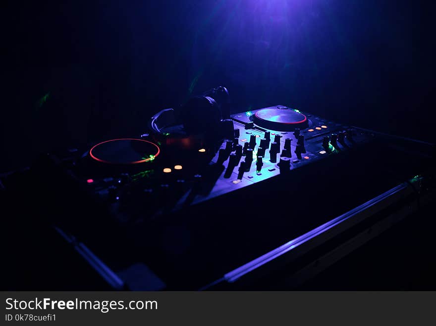 DJ Spinning, Mixing, and Scratching in a Night Club, Hands of dj tweak various track controls on dj's deck, strobe lights and fog, or Dj mixes the track in the nightclub at party. Selective focus