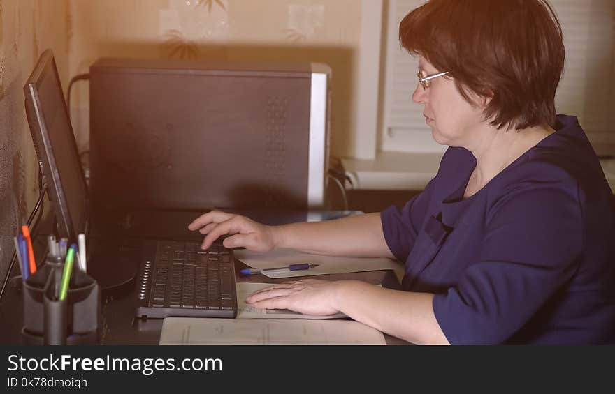 Remote work. A middle-aged woman wearing glasses is sitting at the computer