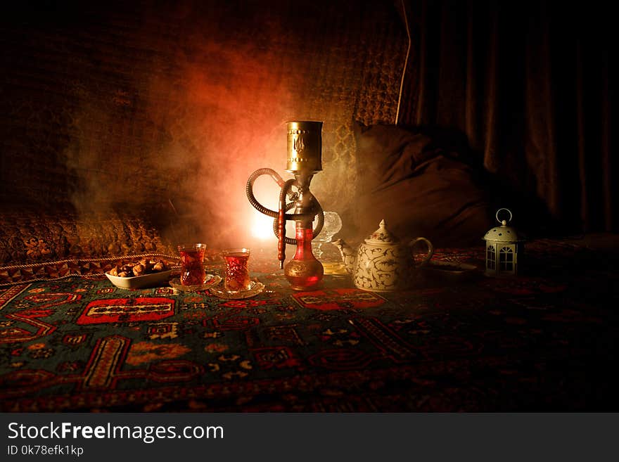 Hookah hot coals on shisha bowl making clouds of steam at Arabian interior. Oriental ornament on the carpet eastern tea ceremony.