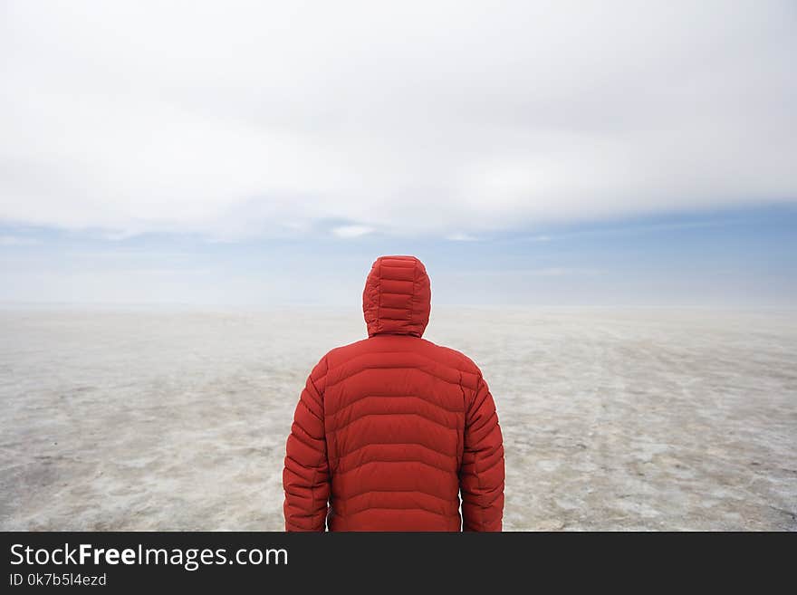 Young man in winter hooded jacket at Salar de uyuni salt flat in Bolivia