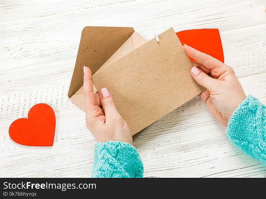 Hand of girl writing love letter on Saint Valentines Day. Handmade postcard with red heart shaped figure. 14 February holiday celebration. Valentine day concept with copy space.