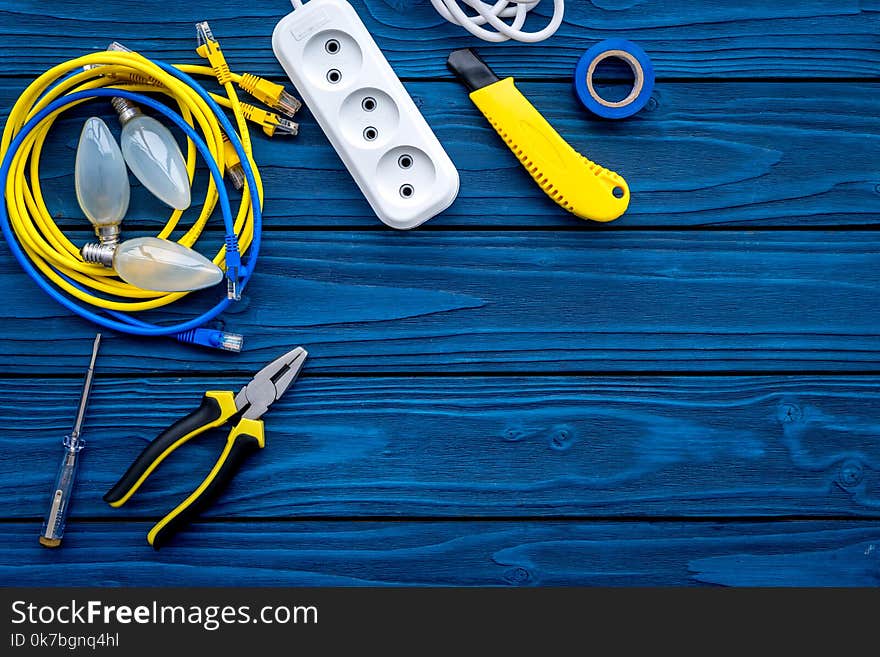 Electrical repair. Bulbs, socket outlet, cabel, screwdriver, pilers on blue wooden background top view copy space