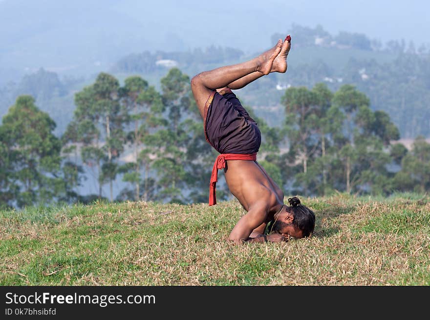 Healthy life exercise concept - athletic Indian man doing handstand outdoors in Kerala, South India. Healthy life exercise concept - athletic Indian man doing handstand outdoors in Kerala, South India