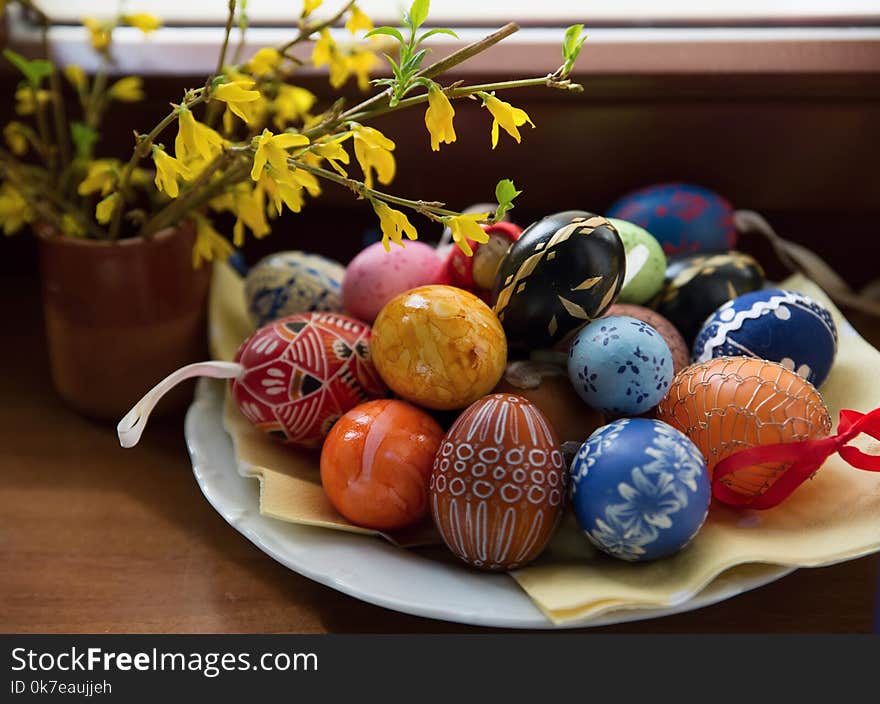 Plate with many color easter eggs and blooming yellow spring flower. Plate with many color easter eggs and blooming yellow spring flower.