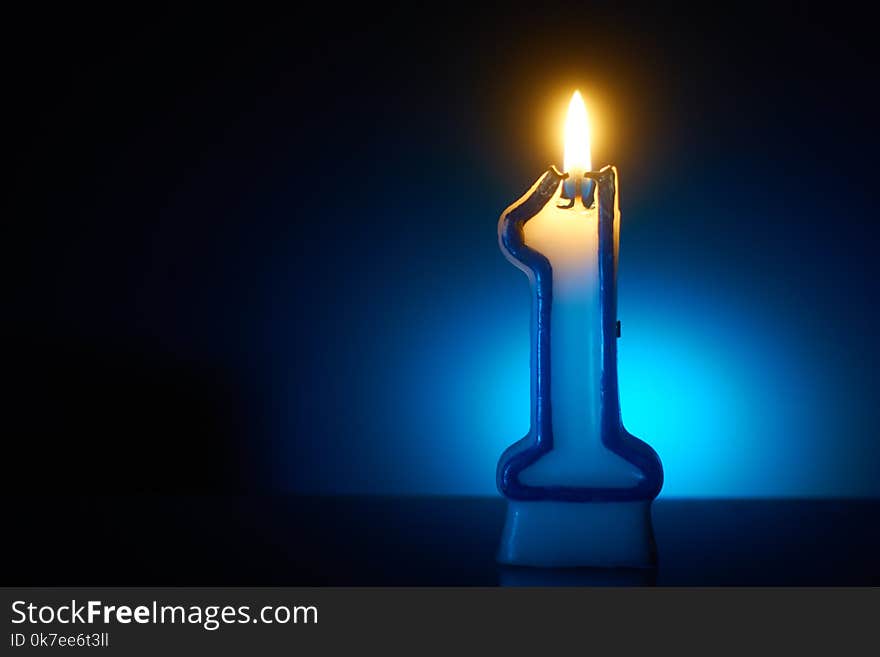 Number One - Burning birthday candle on blue background