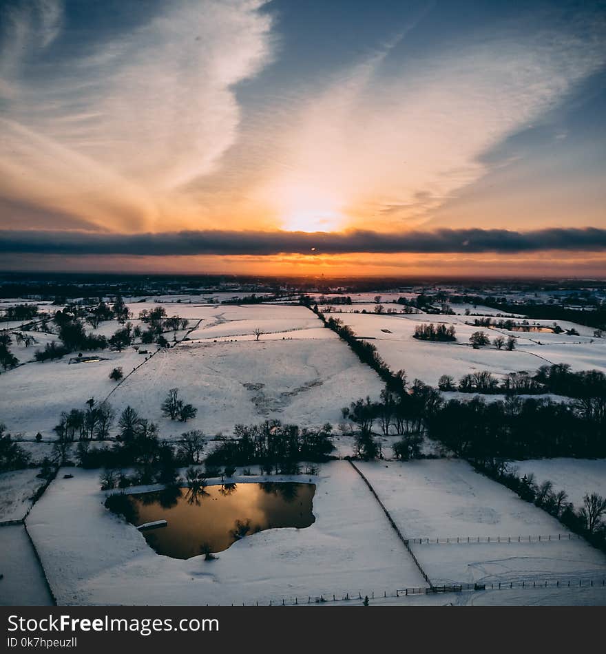 Drone shot of the sky sunset clouds land trees landscape snow