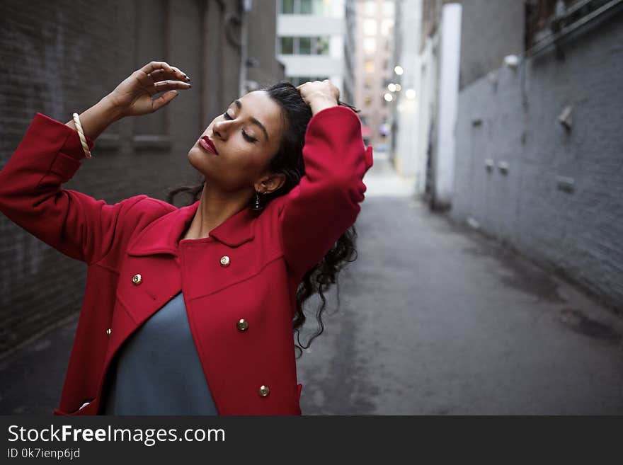 Woman in Red Coat Between Gray Concrete Walls