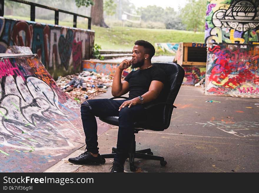 Man Wearing Black Crew-neck Shirt Sitting on Leather Rolling Chair