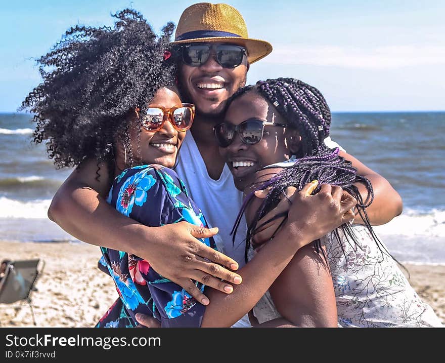 Two Women With Man Hugging by the Sea