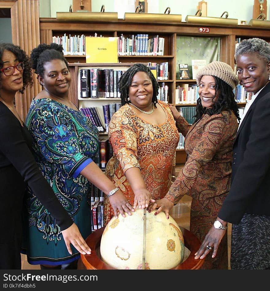 Five Women with Hands on top of a Wooden Globe